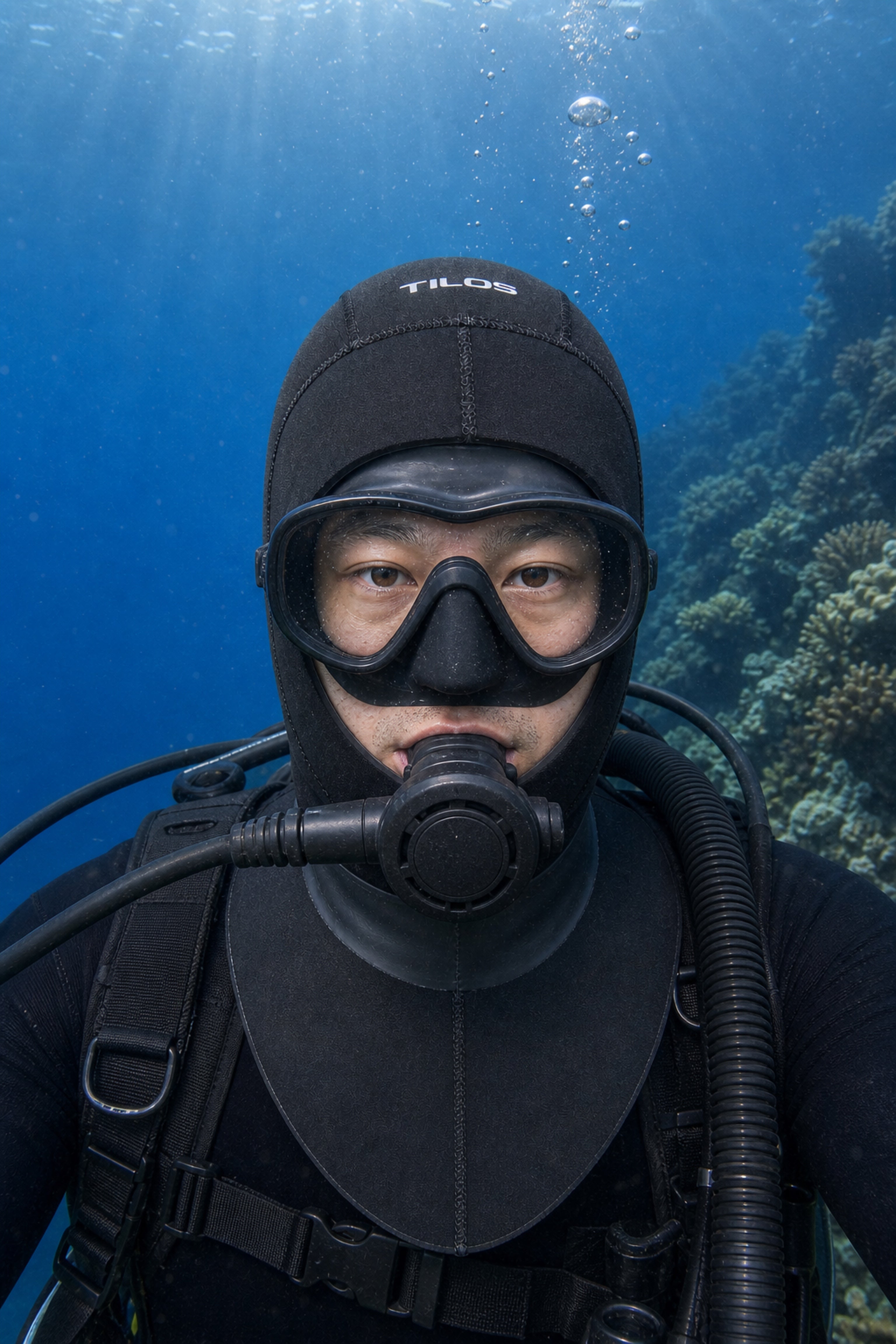 Scuba diver underwater wearing the Tilos H3020 3mm Neoprene Dive Hood, front view over a coral reef